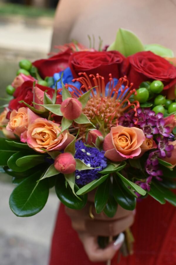 Photo by Lesli Whitecotton Colorful bouquet featuring roses, protea, and greenery, perfect for romantic occasions.
