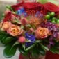 Colorful bouquet featuring roses, protea, and greenery, perfect for romantic occasions.